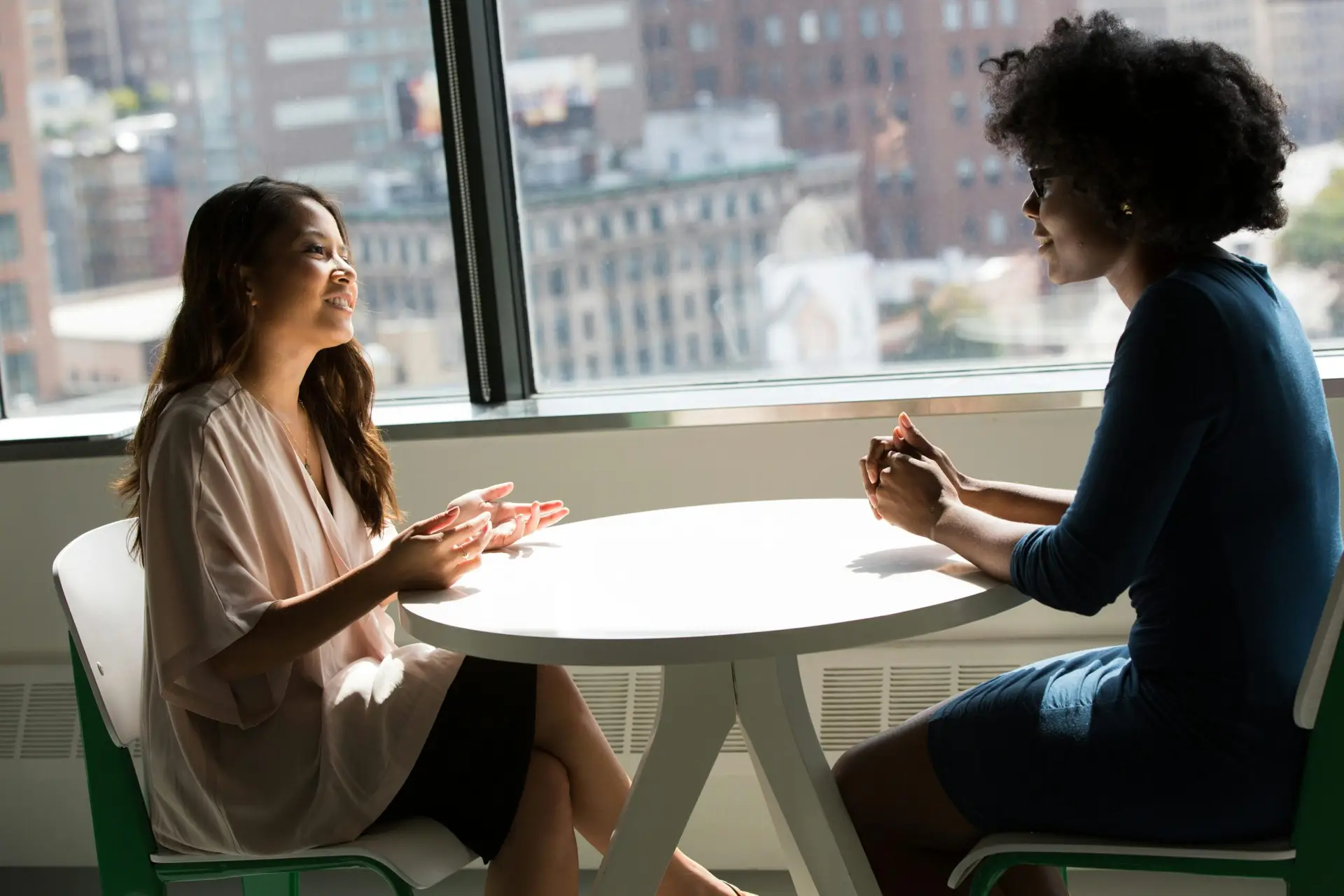 Two women discussing NDIS disability support services in a bright, modern office, focusing on community participation and SIL options.