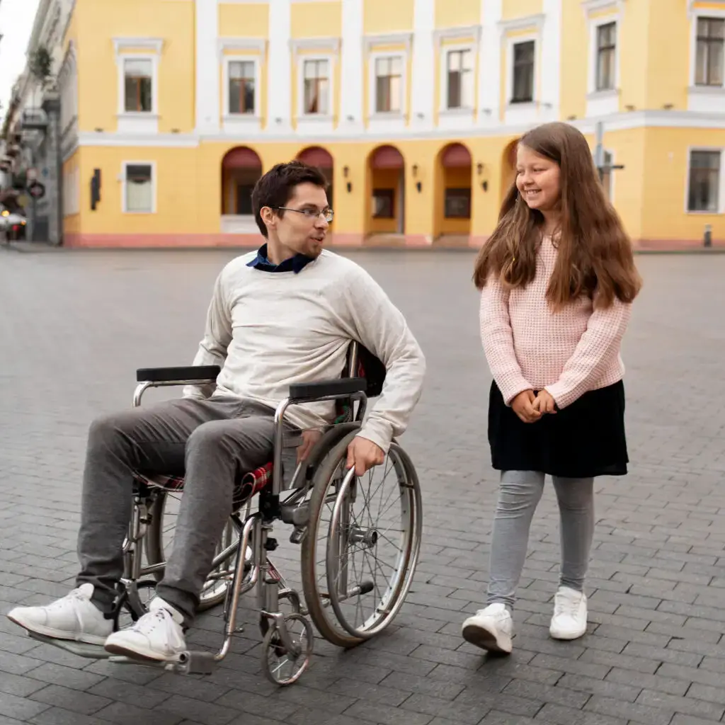 Young girl walking beside a young man in a wheelchair, highlighting community participation in NDIS disability support services.