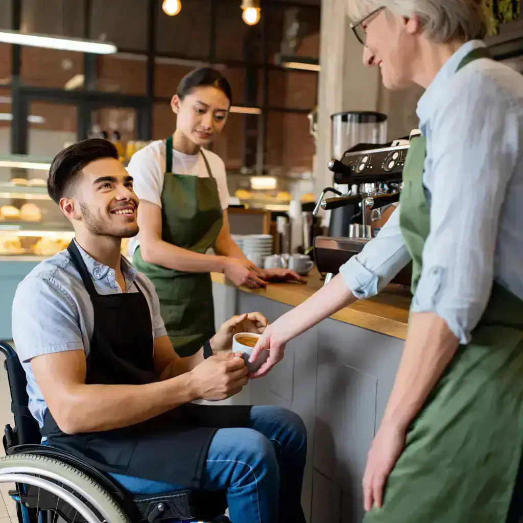 Person in a wheelchair receiving service in a café, highlighting community participation in NDIS disability support services.